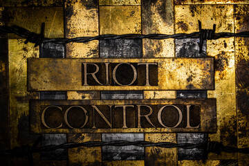 Riot Control text message on textured grunge copper and vintage gold background lined with barbed wire