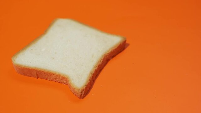 Slices of white bread falling on orange background. Shot of slow motion.