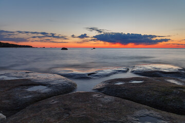 Beautiful colorful sunset over sea and rocks. Baltic sea. Estonia. Long exposure.