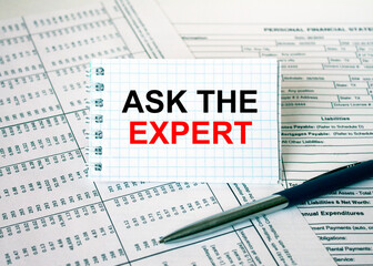 Obraz premium Notepad with text Ask The Expert lying on financial tables with a pen