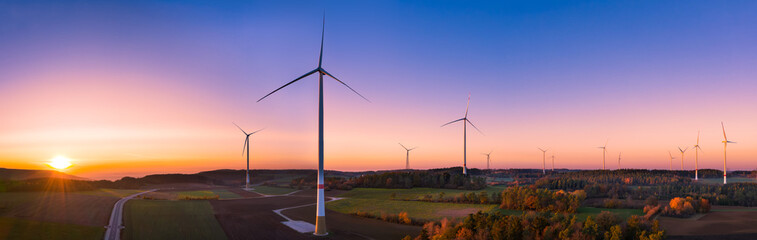 Aerial view of colorful autumn sunset between wind turbines