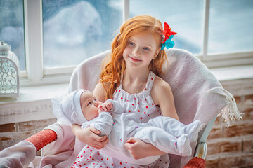 Charming pretty girl teenager holds in her arms her younger newborn sister. Older sister holding body of her little sibling. Concept of Siblings friendly in children. Baby care concept