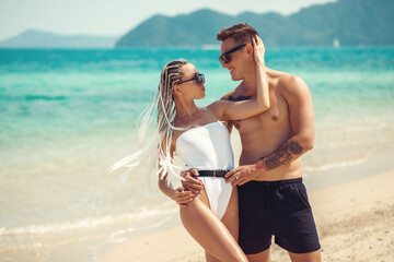 A romantic couple on the beach in a swimsuit, beautiful sexy young people. girl with  white...