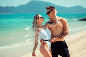 A romantic couple on the beach in a swimsuit, beautiful sexy young people. girl with  white...