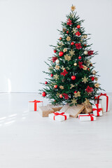 christmas tree with colorful balls and gift boxes over white wall