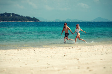 A romantic couple on the beach in a swimsuit, beautiful sexy young people. girl with  white dreadlocks and a man with a tattoo, having fun on the beach. Phuket. Thailand.