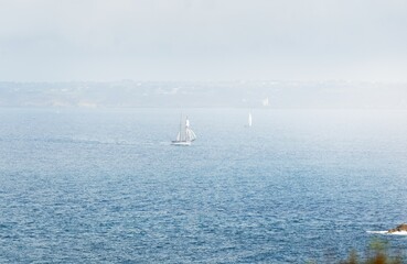 Two-masted gaff schooner (tall ship) and modern white yacht near the rocky shores of Brittany, France. Travel, history, transportation, sailing, sport, cruise, regatta. Panoramic aerial view