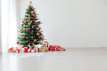 Big beautiful christmas tree decorated with beautiful shiny baubles and many different presents on wooden floor.