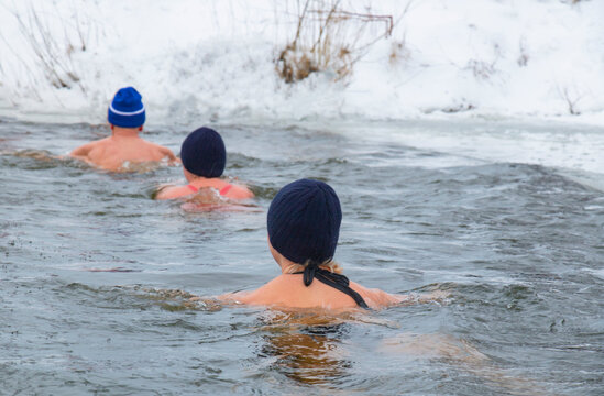 woman and men extreme winter swimming, in winter in frost swim in ice water