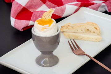 Desayuno tradicional con huevo pasado por agua, mojando el pan en la yema de huevo.