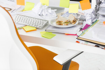 Closeup of sandwich and documents at computer desk in office