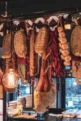 Prosciutto (dry-cured ham) legs meat, different sausages and a bunch of garlic and pepper hangs in...