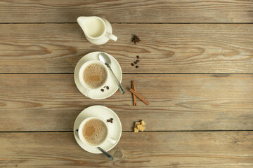 White cups of coffe, milk and spices on a wooden table