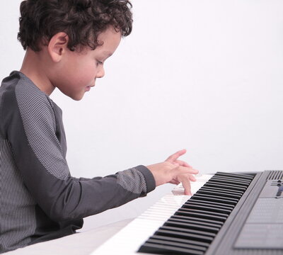 Boy Playing The Piano Keyboard On White Background Stock Photo