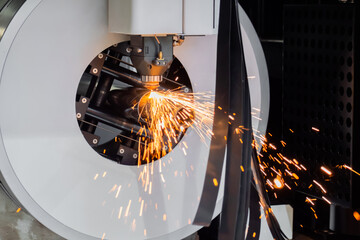 Automatic cnc laser cutting machine working with cylindrical metal workpiece with sparks at factory, plant. Metalworking, machining, industrial, equipment, technology, manufacturing concept