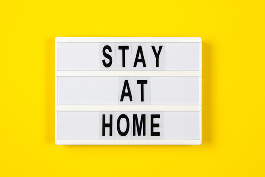 White lightbox with text STAY AT HOME on yellow background. Healthcare, medical, quarantine concept. Top view, copy space - Powered by Adobe