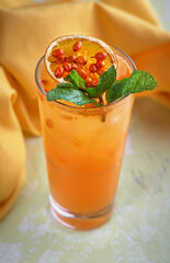Fresh cocktail with sea buckthorn, juice, mint and ice in glass on light stone background. Summer drinks and cocktails