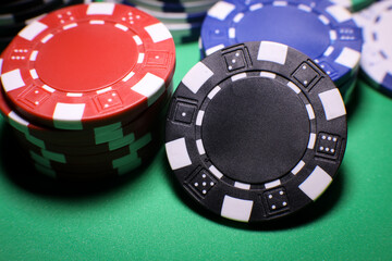 Different poker playing chips on a green table against black background. Online gaming. 