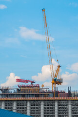 Fototapeta na wymiar Moving yellow tower cranes and unfinished building construction against summer cloudy blue sky. Building process, architecture, urban, engineering, city developing industrial concept