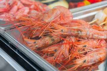 Cooked fresh red langoustine shrimps, prawns in restaurant food container at summer local market - close up. Outdoor cooking, gastronomy, seafood, takeaway, street food concept