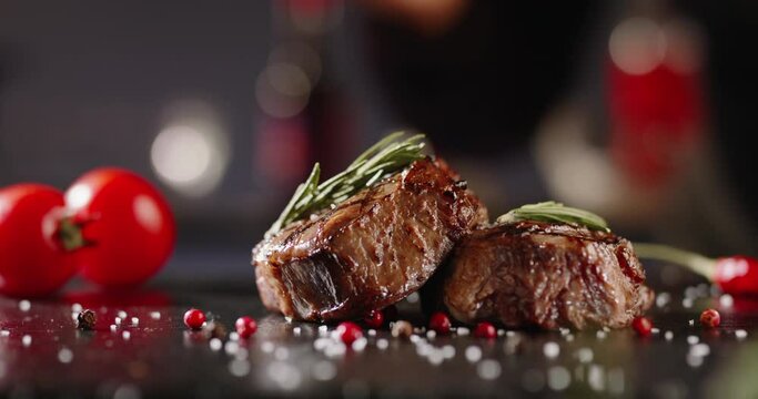 Chef decorating a plate with freshly grilled meat . Cooker adding a piece of rosemary with tweezers on top of steak - food art gourmet dinner 4k footage close up