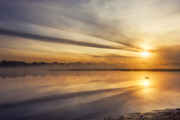 Fototapeta na wymiar Golder sunrise over calm foggy river