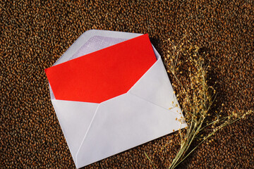 White envelope and red-letter with dried grass for greeting mockup seasonal concepts © Anggit Ruswanto/Wirestock