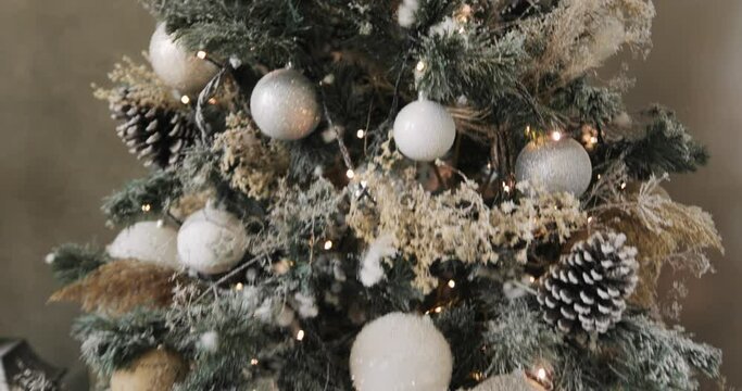 Happy New Year, Christmas, Xmas, holiday and celebration concept. Closeup of Christmas tree decorated with balls, garlands and pompons, camera in motion. Artificial fir tree with a white coating.