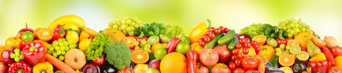 Wide pattern of ripe fruits and vegetables on green background.