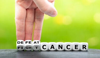 Hand turns dice and changes the expression "fight cancer" to "defeat cancer".