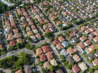 Aerial top down view flying over city showing neighborhood family houses real estate with orange red roofs and gardens