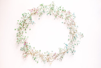small multi-colored flowers with baby's breath arranged in a circle shape of the wreath . flat lay....