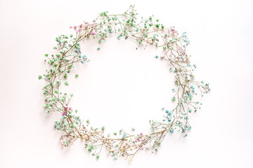 small multi-colored flowers with baby's breath arranged in a circle shape of the wreath . flat lay....