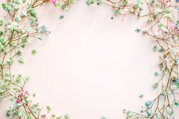 small multi-colored flowers with baby's breath arranged in a circle shape of the wreath . flat lay....