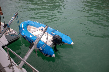 Small blue inflatable boat floating near a yacht, regatta concept. Selective focus
