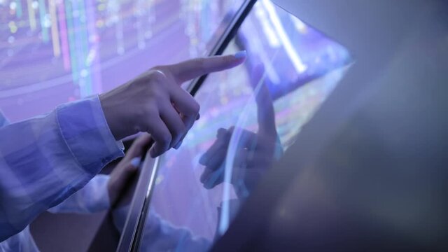 Education, entertainment, learning, technology concept - close up view of woman hand using interactive touchscreen display of electronic kiosk at modern museum or exhibition - scrolling and touching