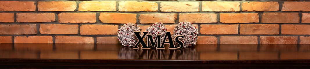 Xmas inscription and Christmas decorations on the background of an old brick wall.

