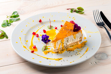 Cheesecake decorated with edible flowers on white plate. a piece of cheesecake on a white wooden table