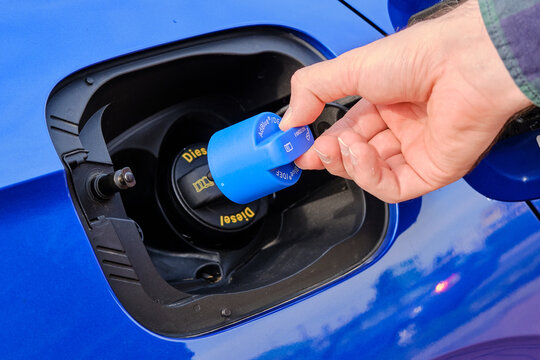 Close up mans hand opening a tank for Ad Blue fluid of a blue car. Diesel exhaust fluid or DEF for reduction of air pollution, October 2020, Prague, Czech Republic