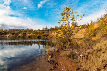 Sandy slope on the shore of the lake . Autumn landscape.