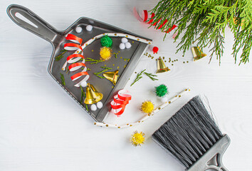 Christmas cleaning after the mess. Cleaning tools broom and scoop and unused Christmas decorations after party top view flat lay on white background. Concept of cleaning after holiday,