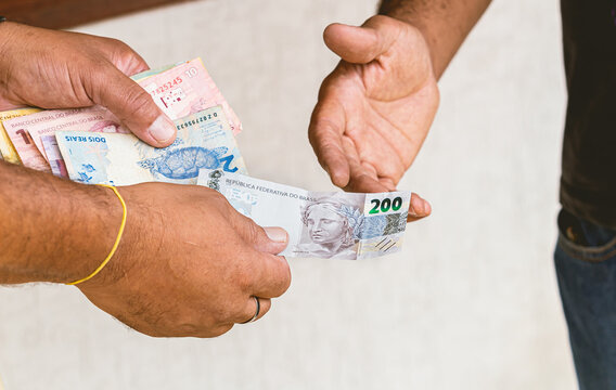 Real, Real Brasileiro, Reais, Dinheiro, Brasil. Homem fazendo um pagamento com c&eacute;dulas brasileiras. Nota de 200 Reais em destaque.