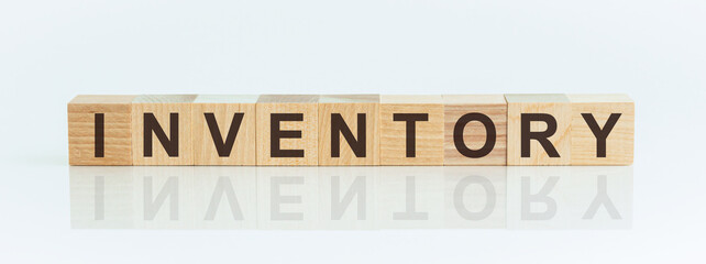 Wooden Blocks with the text: INVENTORY. The text is written in black letters and is reflected in the mirror surface of the table.