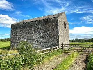 Old stone barn, next to the Hellifield Road, with fields, and trees beyond in, Bolton by Bowland, Clitheroe, UK