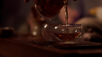 Japanese tea master plunges into the atmosphere of a real tea ceremony, pours strong pu'er tea into a cup from a flask.