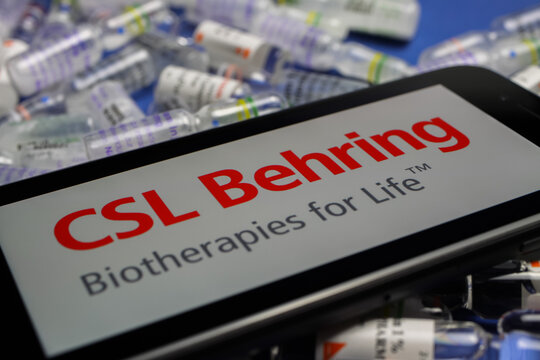 Viersen, Germany - May 9. 2020: Close up of mobile phone screen with logo lettering of CSL Behring biotherapies pharmaceutical company on pile drug ampules
