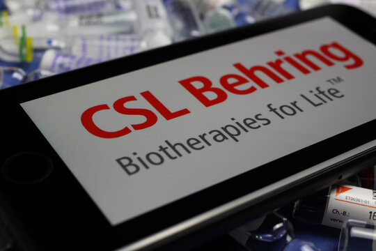 Viersen, Germany - May 9. 2020: Close up of mobile phone screen with logo lettering of CSL Behring biotherapies pharmaceutical company on pile drug ampules