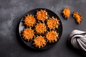 Traditional karelian, finnish, russian mini pies "kalitki" or "koliadki" stuffed with carrots and rice on black textured background, flat lay © olepeshkina