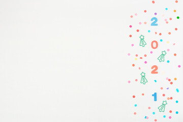 Multi-colored soft English numbers 2021 with Christmas tree formed clips on white background with paper confetti. Back to school, Christmas in office concept. Flat lay, copy space.