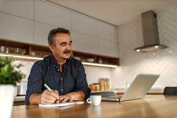 Obraz premium Using notebook and pen, laptop and cup of coffee on the desk.